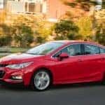 A red 2016 Chevy Cruze is shown from the side on a city street.