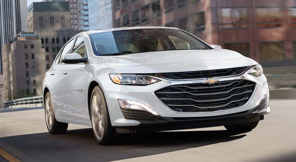 White 2021 Chevy Malibu driving down a bridge.