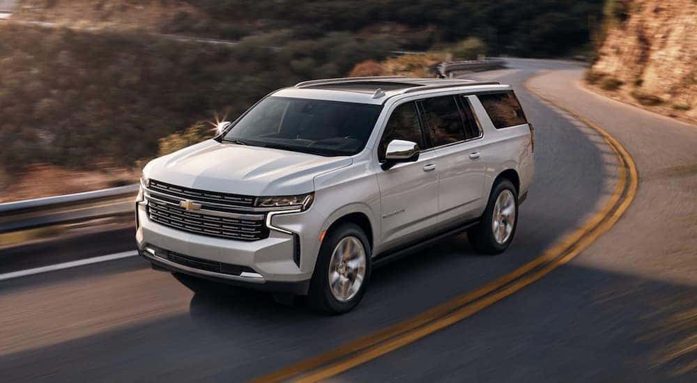 White 2021 Chevy Suburban driving down a winding road.