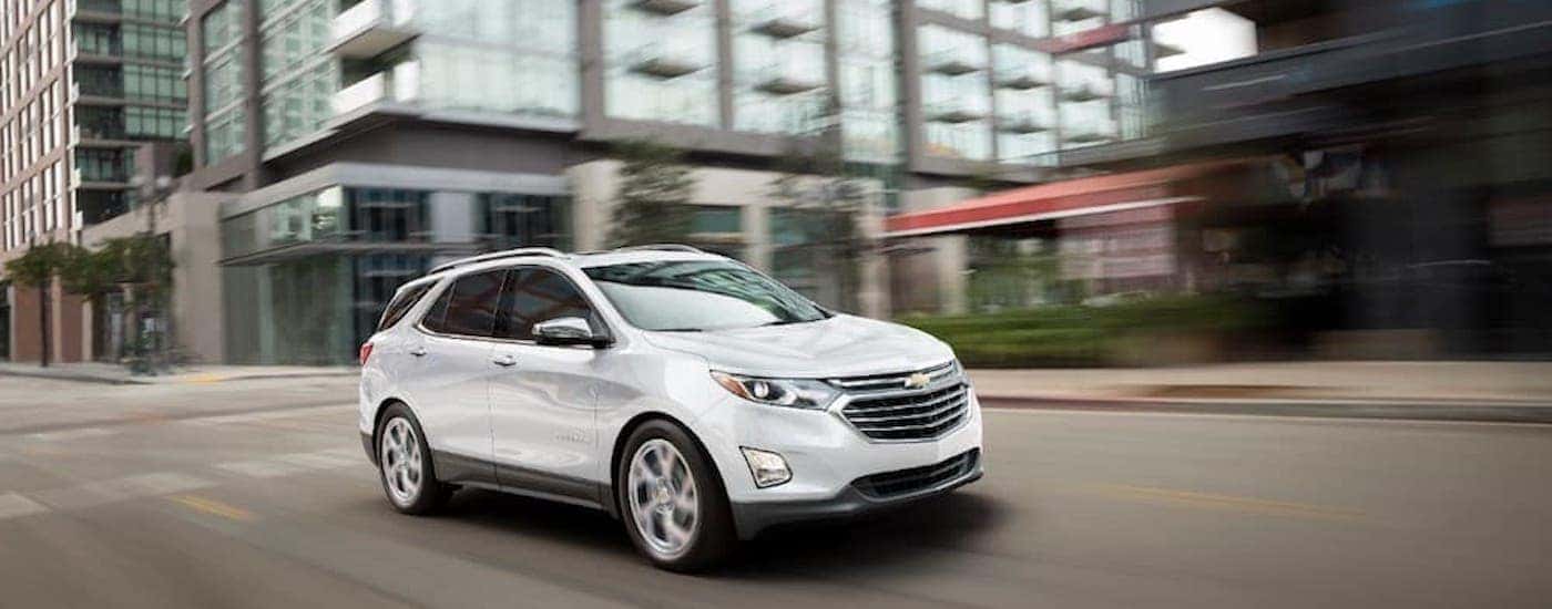 A white 2018 Chevy Equinox is shown from the side on a city street.
