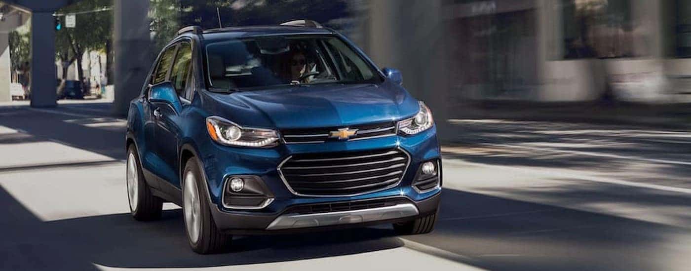 A blue 2020 Chevy Trax is shown driving on a city street.