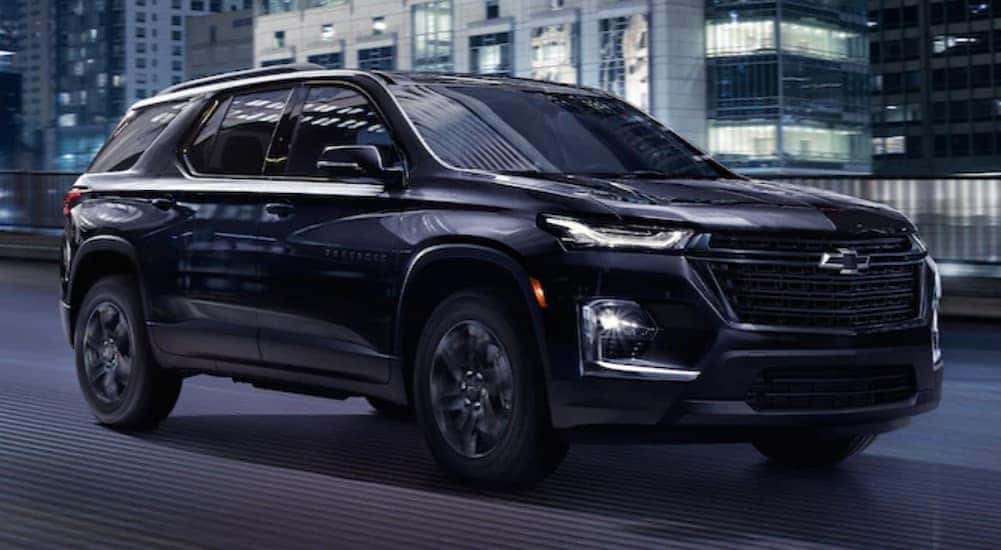 Black 2023 Chevy Traverse, a CPO Chevy, driving on a city street.