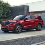 A red 2023 Ford Explorer Hybrid is shown parked in a driveway after visiting a dealer with a used SUVs for sale.