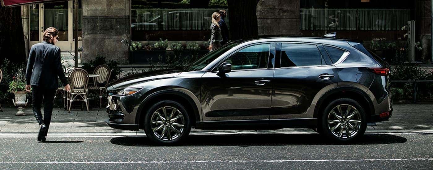 A black 2020 Mazda CX-5 is shown from the side stopped at a crosswalk.