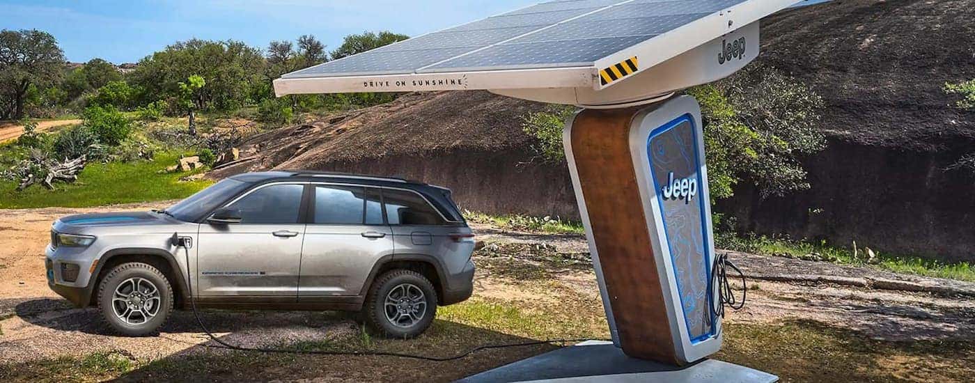 A grey 2022 Jeep Grand Cherokee 4xe is shown parked at a remote EV charging station.