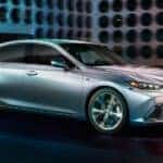 A silver 2021 Lexus ES is shown driving in a city after viewing used cars for sale in Albany.