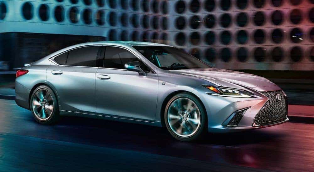 Silver 2021 Lexus ES driving through a city after viewing used cars for sale in Albany.