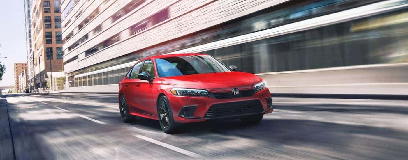 A red 2022 Honda Civic is shown driving on a city street.