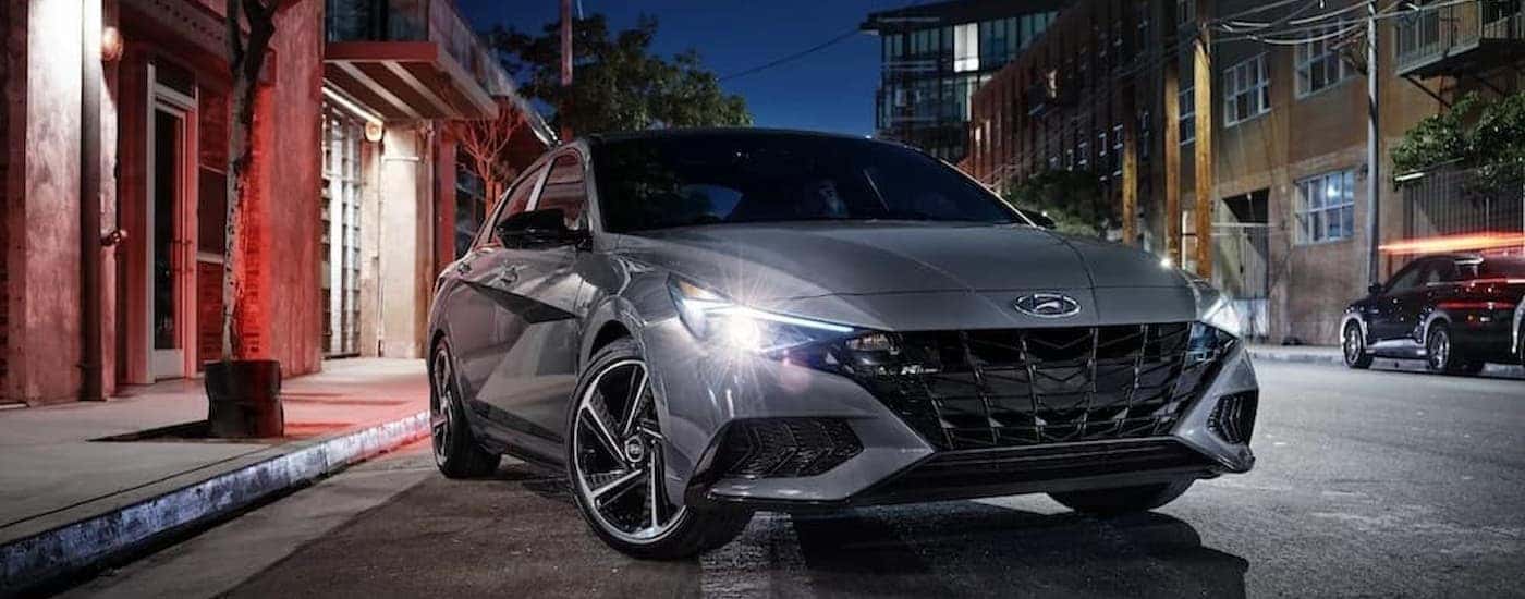 A silver 2023 Hyundai Elantra is shown parked near a curb at night.