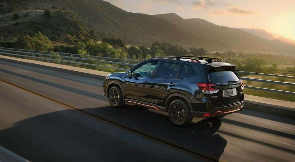 A black 2021 Subaru Forester is driving on an open highway.
