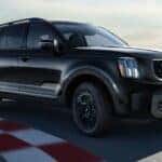 A black 2022 Kia Telluride X-Line is driving on a track after viewing used cars for sale in Albany.