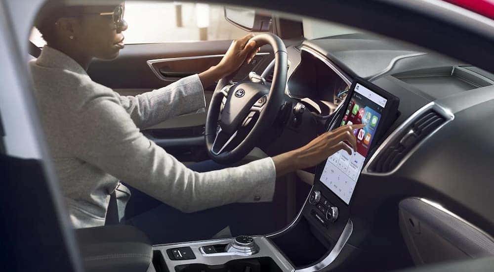 A woman is driving in a 2022 Ford Edge while test driving used cars for sale near Colonie.