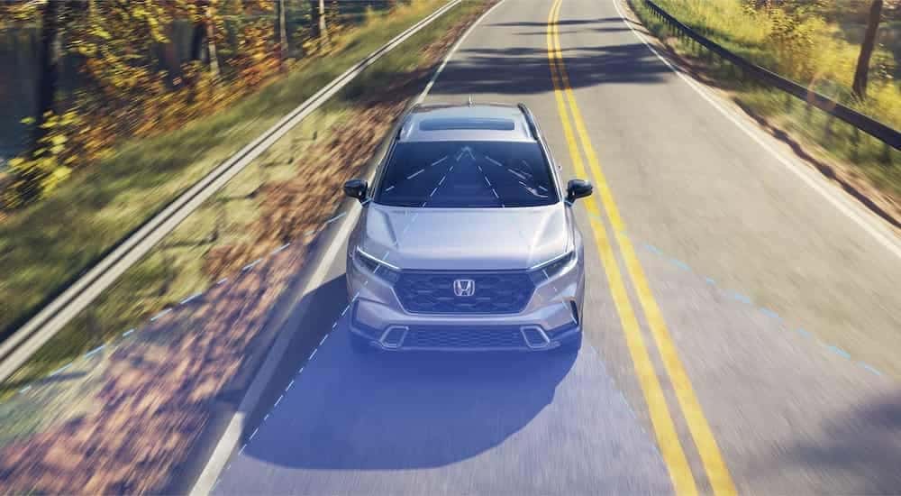 A grey 2024 Honda CR-V is driving with simulated Honda sensing lines.