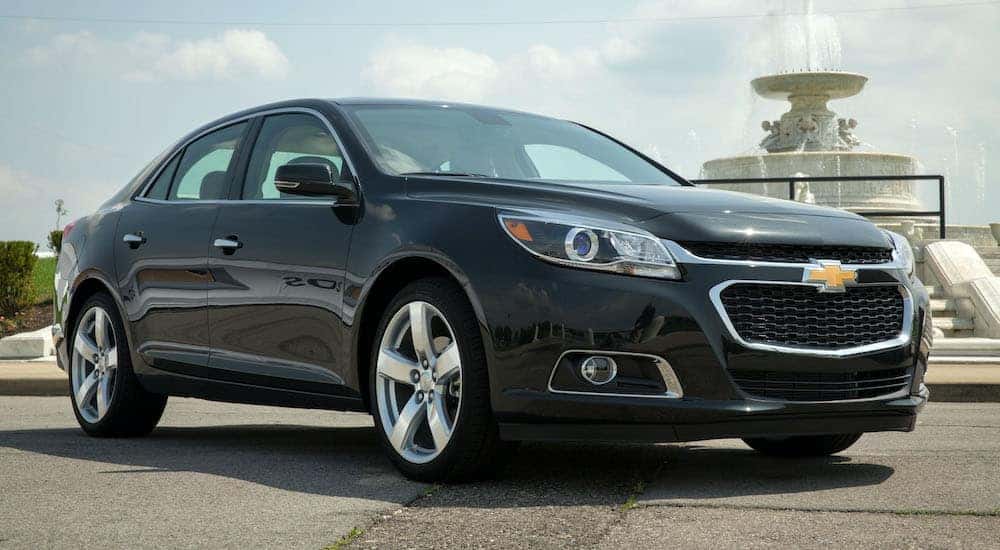 Black 2014 Chevy Malibu parked by a dealer with used cars for sale near Amsterdam.