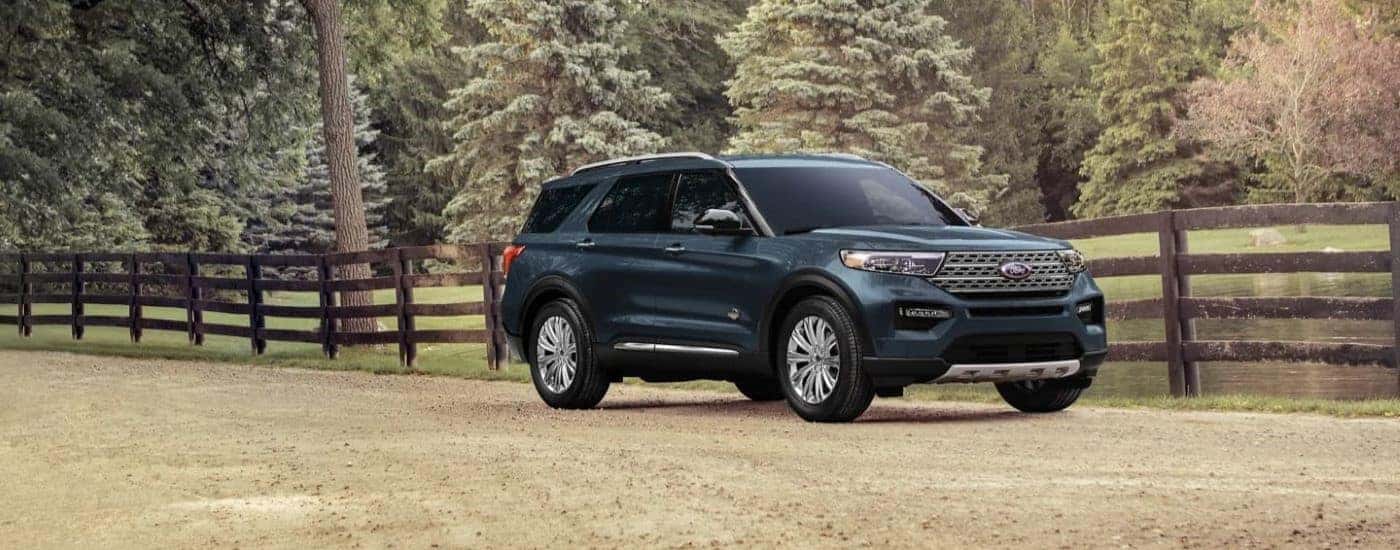 A black 2023 Ford Explorer King Ranch driving by a fence.