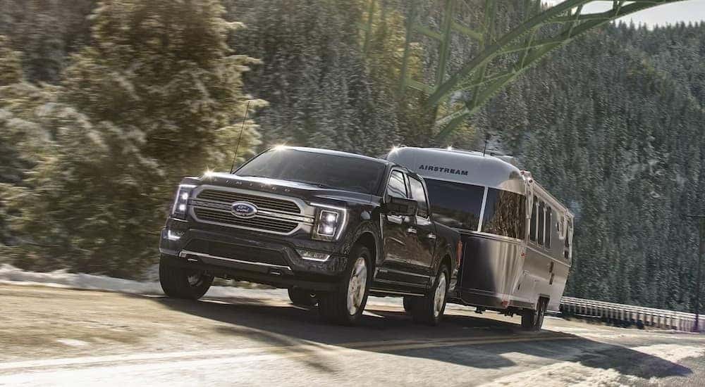 A black 2023 Ford F-150 Limited is shown towing a trailer.