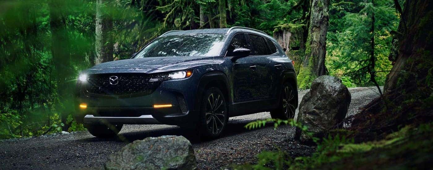 A black 2023 Mazda CX-50 driving through the woods.