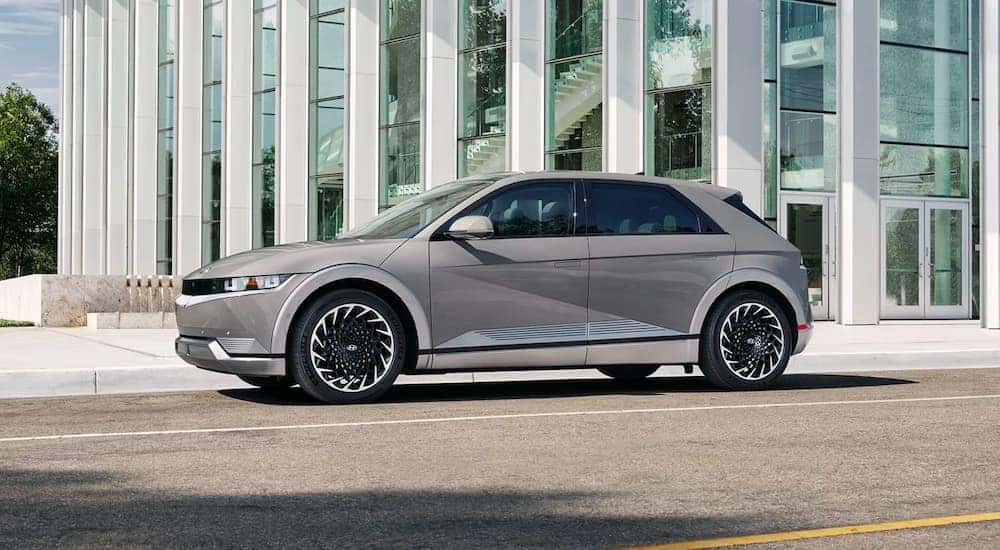 A silver 2023 Hyundai IONIQ 5 is shown parked near a city building.