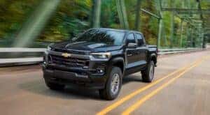 A black 2023 Chevy Colorado is shown driving on a bridge after viewing used trucks for sale in Albany.