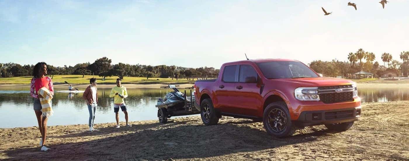 A red 2023 Ford Maverick FX4 is shown parked near a pond.