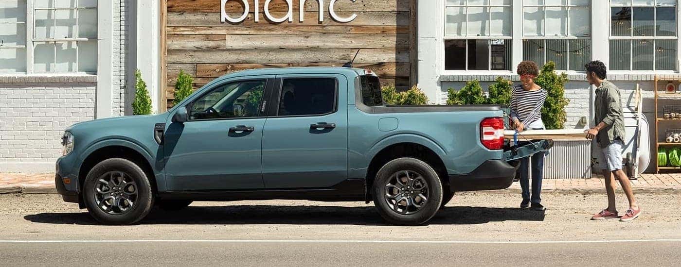 A blue 2023 Ford Maverick is being loaded with supplies after viewing used trucks for sale near Troy.