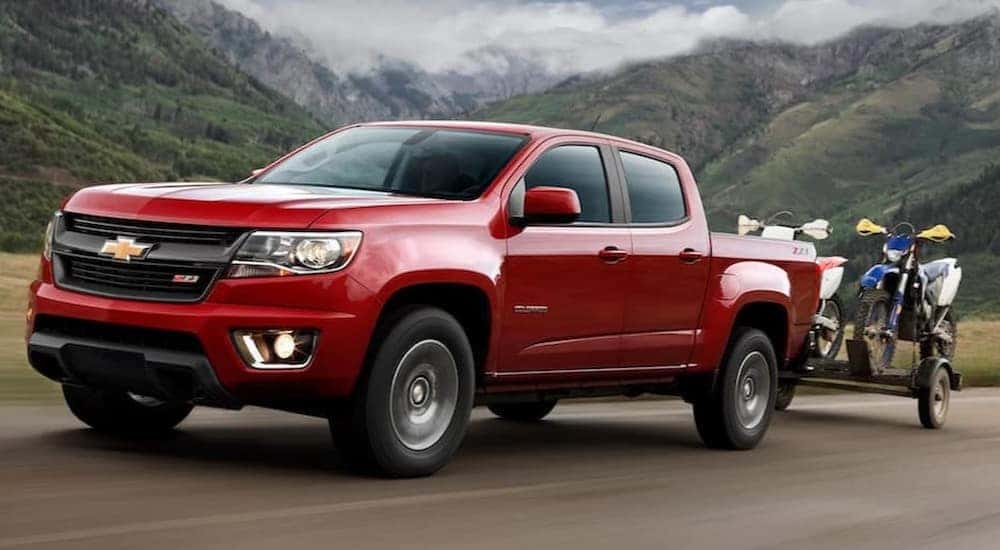 A red 2020 Chevy Colorado Z71 is shown towing a trailer on a highway.