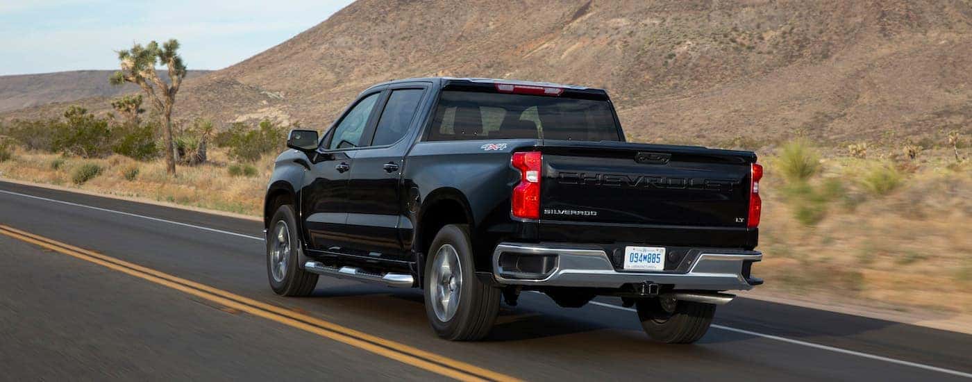 Black 2022 Chevy Silverado 1500 LT driving down a desert road.