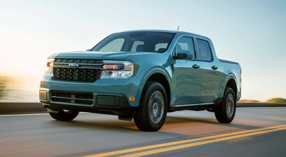 Teal 2023 Ford Maverick XLT driving down a road.