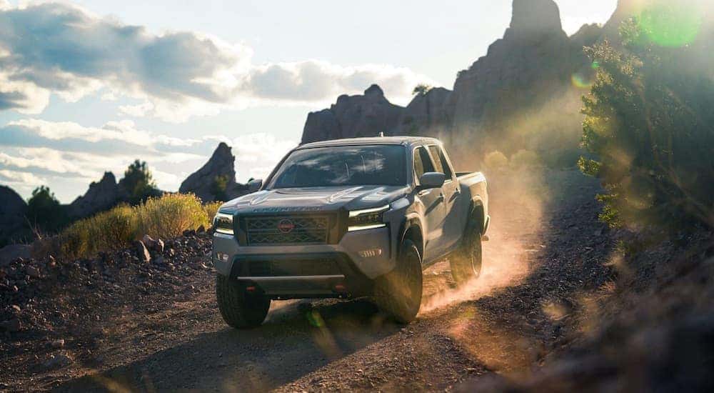 Grey 2023 Nissan Frontier Pro-4x driving down a hill.