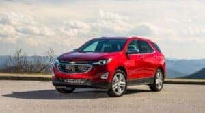 A red 2020 Chevy Equinox parked by a used car dealership.