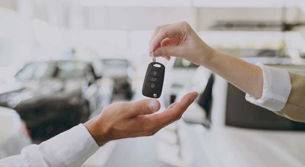 Two people are shown exchanging a key fob.
