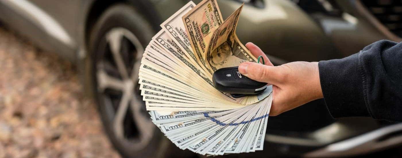 A person is shown holding money and a key fob.