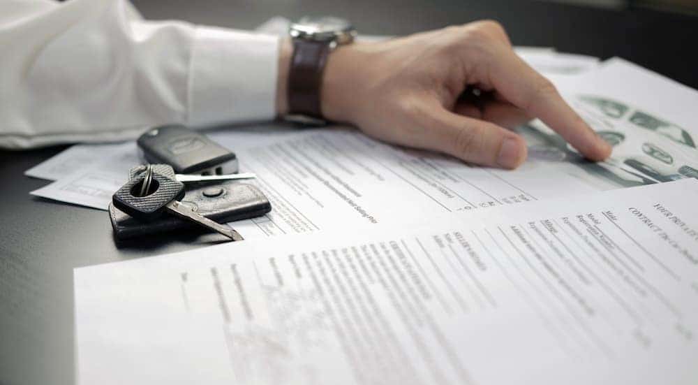 A person is shown pointing at "sell my car" paperwork.