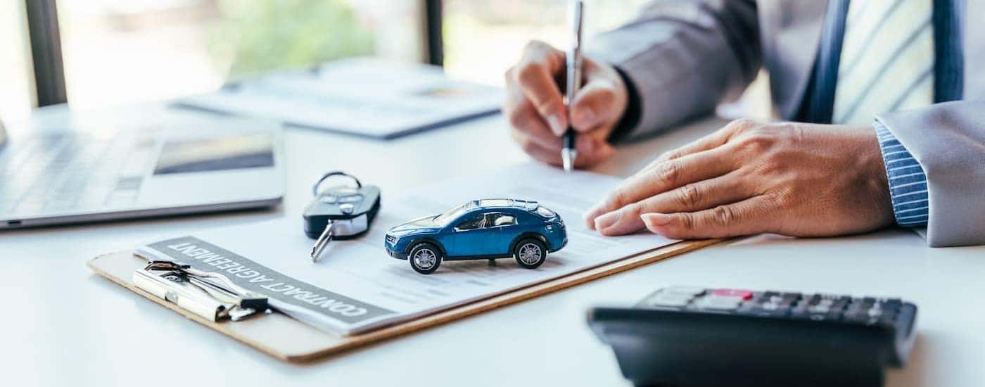 A person is shown signing a document to 'sell my car.'