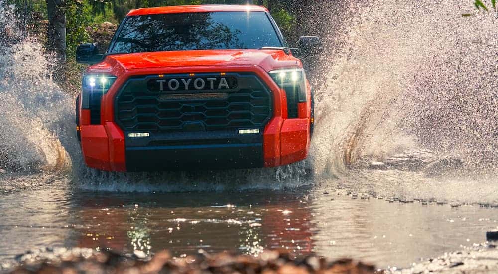 Red 2022 Toyota Tundra TRD Pro driving through a shallow pond.