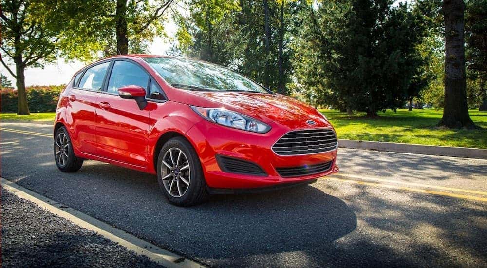 Red 2015 Ford Fiesta driving down a street.