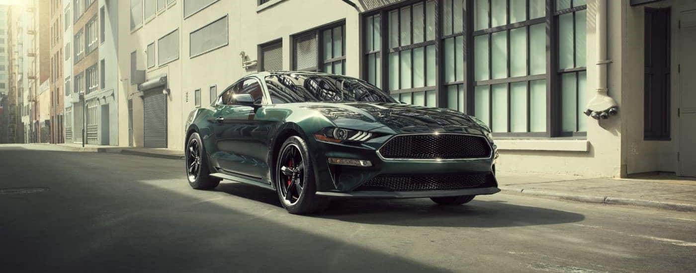 A dark green 2020 Ford Mustang, a used Ford for sale in Albany, parked by a building.