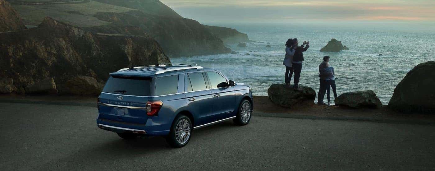 A blue 2023 Ford Expedition parked by an ocean shore.