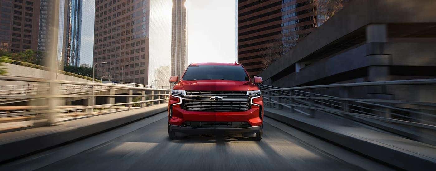 Red 2023 Chevy Tahoe, a used Chevy for sale in Albany, driving on a highway.