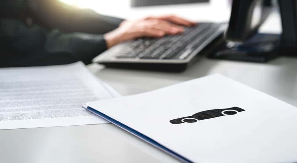 Salesman on a computer next to insurance paperwork