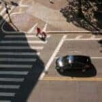 Car stopped at a crosswalk near a used car dealership