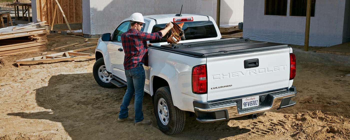 Man putting gear in the bed of a white 2022 Chevy Colorado