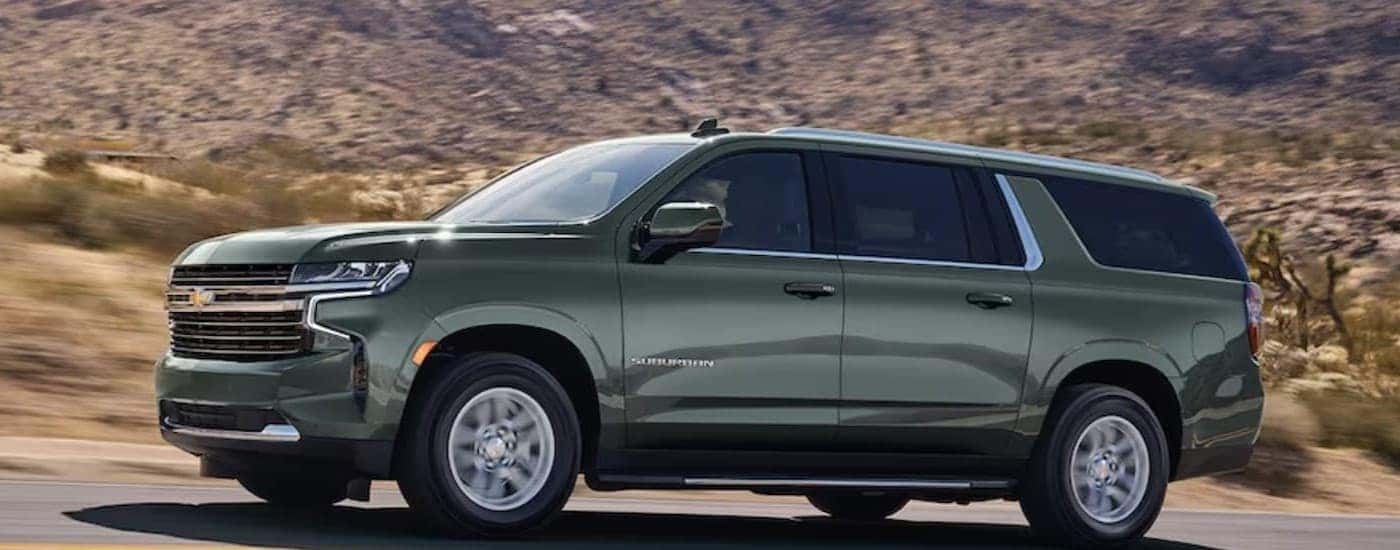A green 2024 Chevy Suburban driving on a highway.