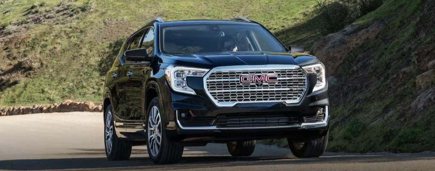 A black 2024 GMC Terrain driving to view used SUVs for sale in Albany.