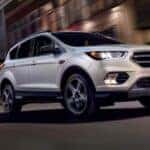 White 2019 Ford Escape driving down a road from a dealer with used SUVs for sale near Colonie.