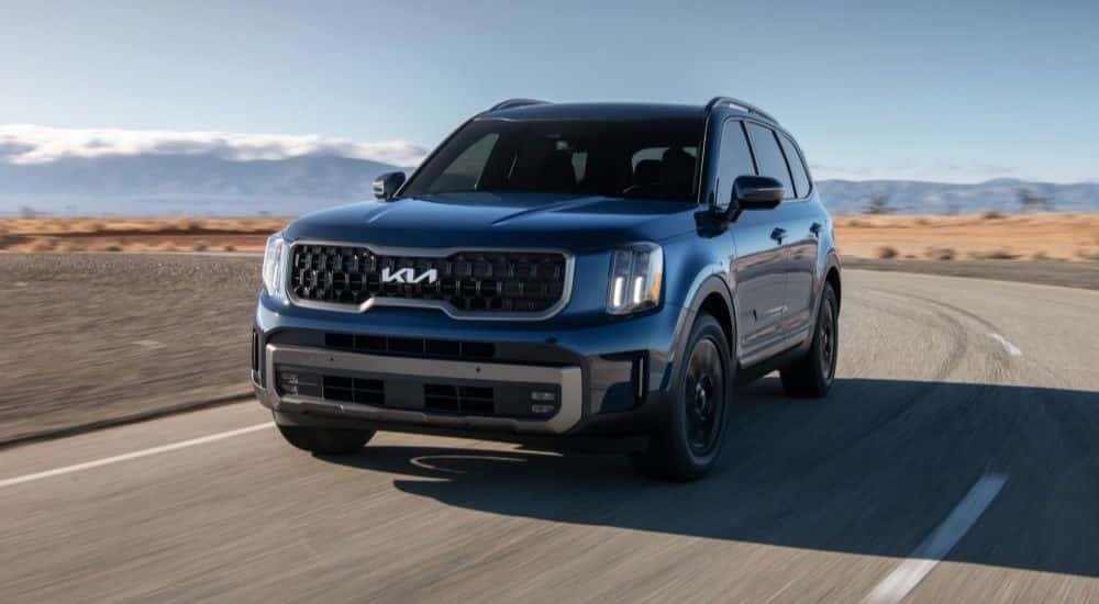 Black 2023 Kia Telluride driving down a road.