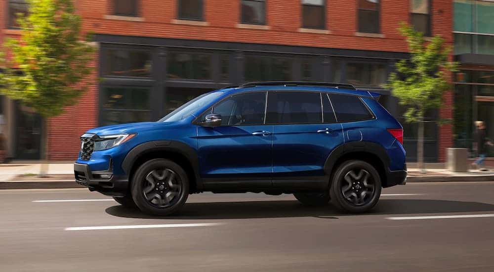 A blue 2023 Honda Passport Elite driving in a city