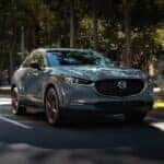 A gray 2023 Mazda CX-30 driving down a street
