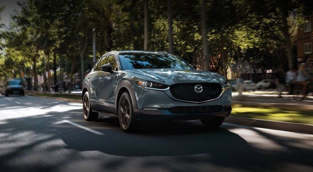 A gray 2023 Mazda CX-30 driving down a street