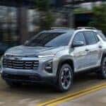 A silver 2025 Chevy Equinox driving down a city street